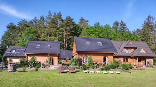 a log home with solar panels on its roof at Woodorf drewnem usłane - domki z bala nad rzeką Słupią wśród pól i lasów z chatą grillową, ogniskiem i placami zabaw dla dzieci -Royal Red House z jacuzzi i ogrodzonym extra ogródkiem dla piesków, Royal Green House - bez jacuzzi in Ustka