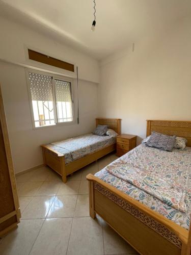 um quarto com 2 camas e 2 janelas em PROMO Appartement Familial avec WiFi em Al Hoceïma