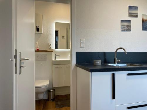 uma casa de banho branca com um lavatório e um WC em Deichperle Krautsand em Drochtersen