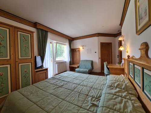 a bedroom with a large bed and a desk at Alpenhotel Panorama in Campitello di Fassa