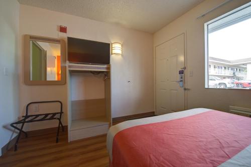 a bedroom with a bed and a window and a chair at Motel 6-Seattle, WA - Airport in SeaTac