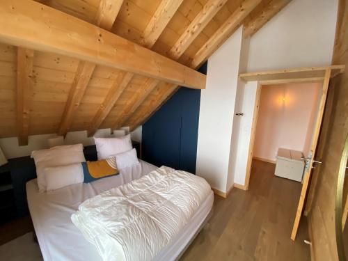 a bed in a room with a wooden ceiling at Chalet La Mahure in La Toussuire