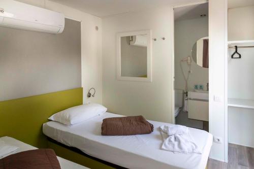 Habitación pequeña con 2 camas y espejo. en hu Venezia Camping in Town, en Marghera