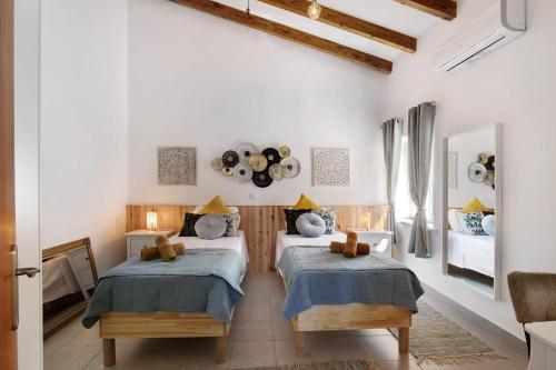 two beds in a room with white walls at Casa de Aloe in Paderne