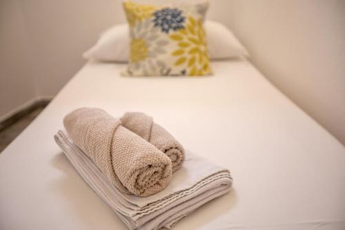 Una cama blanca con toallas y almohadas. en Appartamento Tergu en Tergu