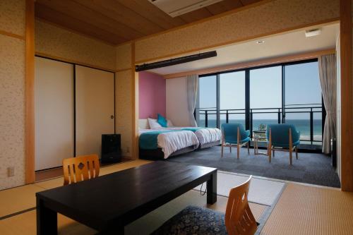 a bedroom with a bed and a table and chairs at シーサイド佐竹 in Kyotango