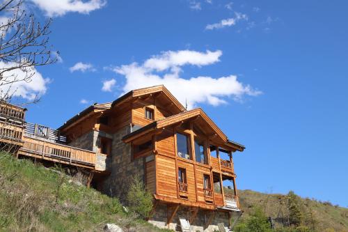 eine Blockhütte auf einem Hügel mit blauem Himmel in der Unterkunft Charming Chalet w/ Mountain & Slope Views, Jacuzzi in Vars