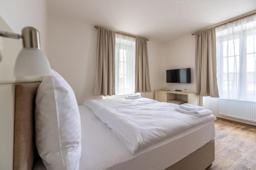 a bedroom with a white bed and a television at Hotel Barborský dvůr in Kutná Hora