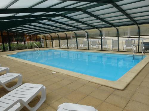 une grande piscine avec de l'eau bleue dans un immeuble dans l'établissement Gite les Acacias - les gites des hauts de vialot, à Auriac-du-Périgord