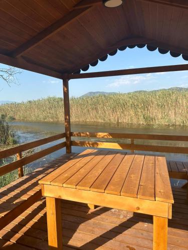 a wooden bench on a deck with a view of a river at 101 Gün Kiralık Lake House Kayacık in Dalaman