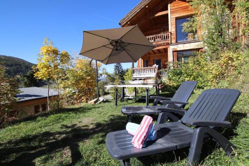 two chairs and a table with an umbrella in front of a house at Charming Chalet w/ Mountain & Slope Views, Jacuzzi in Vars