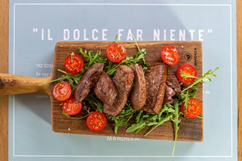 a bunch of sausages on a cutting board with tomatoes at Mandilla in Köveskál