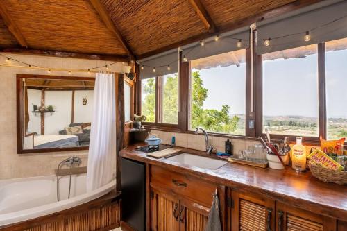 a kitchen with a sink and a tub and windows at Best view Cosmic cabin In Eco village in Clil