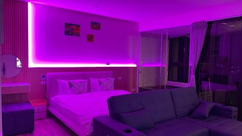 een paarse kamer met een bed en een bank bij 宜蘭頭城鎮 Alice 高級溫泉雙-四人套房海景度假 in Hsin-hsing