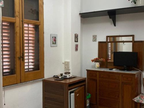 uma sala de estar com uma televisão e um armário de madeira em Bed & Breakfast 5 Di Spade em Gioiosa Marea