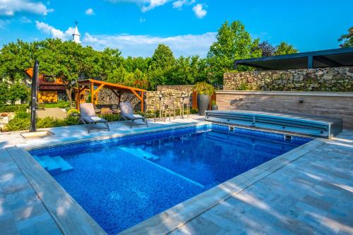 a swimming pool in a backyard with two chairs around it at Mandilla in Köveskál