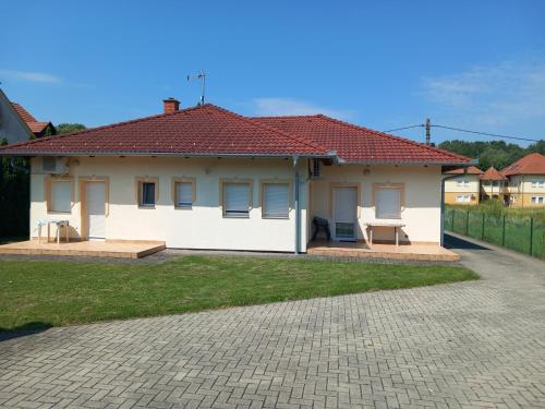 uma pequena casa branca com um telhado vermelho em Petra Apartmanház em Kehidakustány