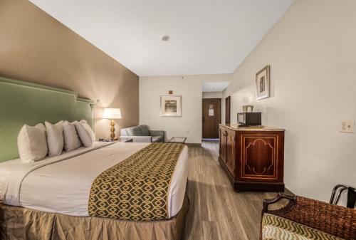 a hotel room with a large bed and a chair at Baymont by Wyndham Orlando-International Dr-Universal Blvd in Orlando