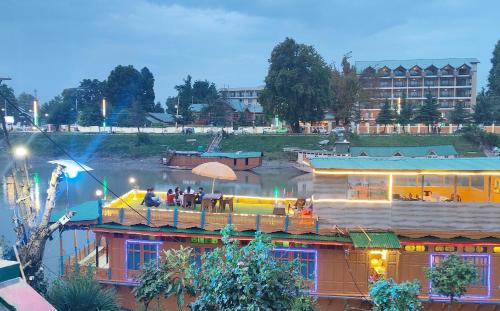 personnes assises dans un bar sur un bateau sur une rivière dans l'établissement Houseboat Karima palace, à Srinagar