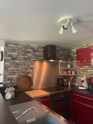 - une cuisine avec des placards rouges et un mur en pierre dans l'établissement La Parenthèse gîte à la campagne, à Fougerolles