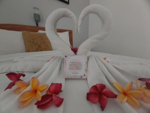 a bed with white sheets and swansomorphic at Genta House in Kuta
