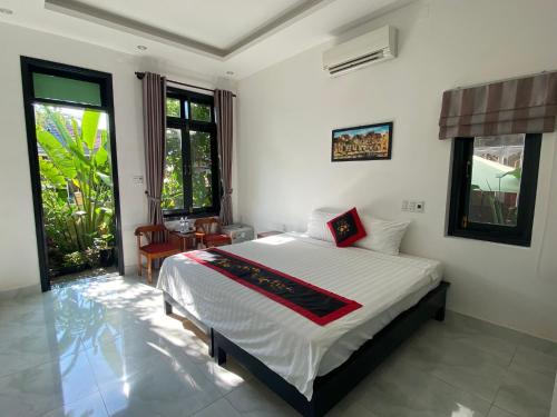 une chambre avec un lit dans une pièce avec des fenêtres dans l'établissement Hoi An Sunny Garden, à Hội An