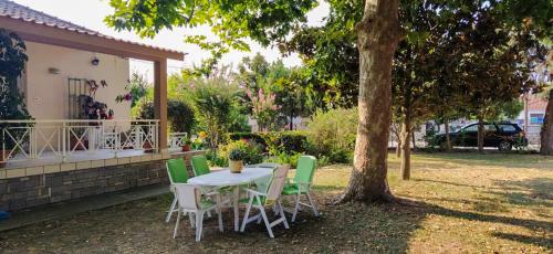 una mesa y sillas bajo un árbol en un patio en Calda Ospitalita, en Néa Karyá