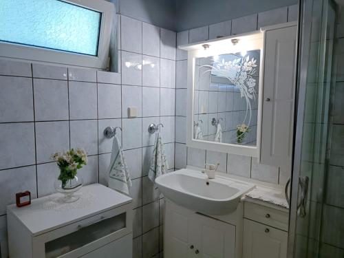 a white bathroom with a sink and a mirror at Calda Ospitalita in Néa Karyá