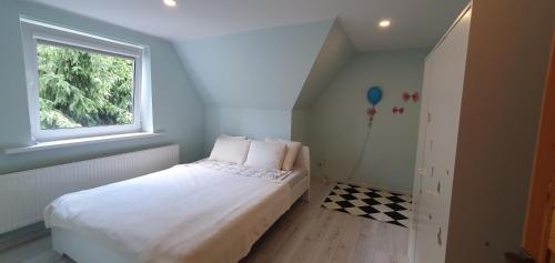 niewielka sypialnia z białym łóżkiem i oknem w obiekcie ŠILAINIŲ APARTAMENTAI w Kownie