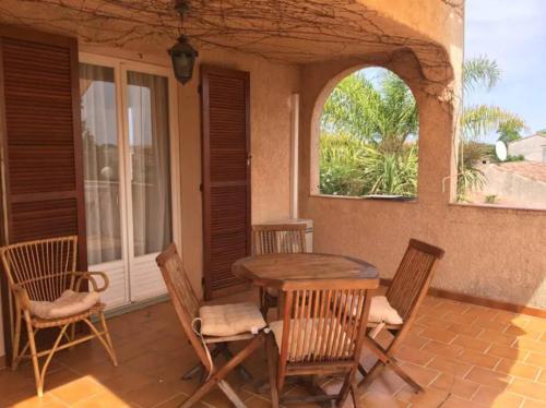 un patio con mesa y sillas en un porche en Mare è Monte , jardin méditerranéen et exotique., en Ghisonaccia