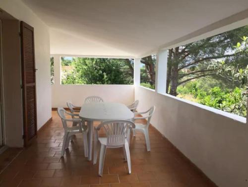 a dining room with a table and chairs and windows at Mare è Monte , jardin méditerranéen et exotique. in Ghisonaccia