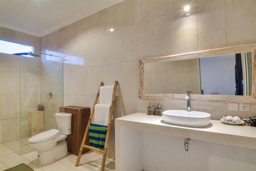 a bathroom with a sink and a toilet and a mirror at Selog Villa 4 in Seminyak