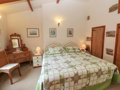 a bedroom with a bed and a dresser and a mirror at Llaethdy Cottage in Haverfordwest