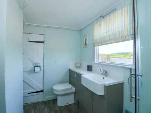 a bathroom with a sink and a toilet and a window at 102 The Beach in Snettisham