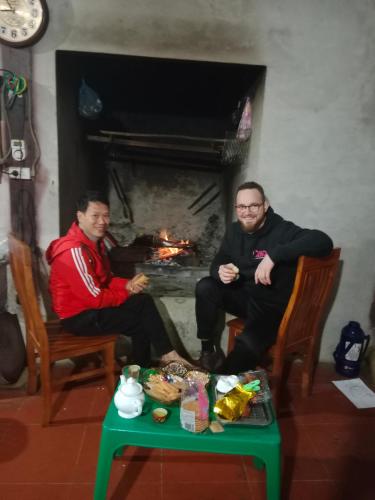 two men sitting in chairs in front of a fireplace at homestay phô núi suôi giang in Yên Bái