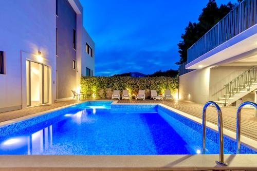 a swimming pool in the backyard of a house at night at Villa Luxury HERMES - Heated Pool, Jacuzzi, Elevator in Podstrana