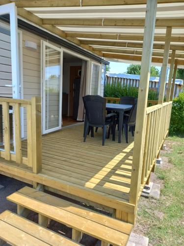 a wooden deck with a table and chairs on it at Mobil-home climatisé 5-6 pers LA PLAGE in Saint-Hilaire-de-Riez
