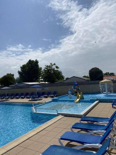 une piscine avec des chaises longues bleues et une fontaine dans l'établissement Mobil-home climatisé 5-6 pers LA PLAGE, à Saint-Hilaire-de-Riez