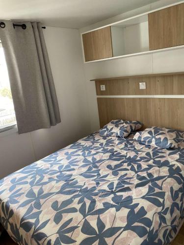 une chambre avec un lit avec une couette bleue et blanche dans l'établissement Mobil-home climatisé 5-6 pers LA PLAGE, à Saint-Hilaire-de-Riez