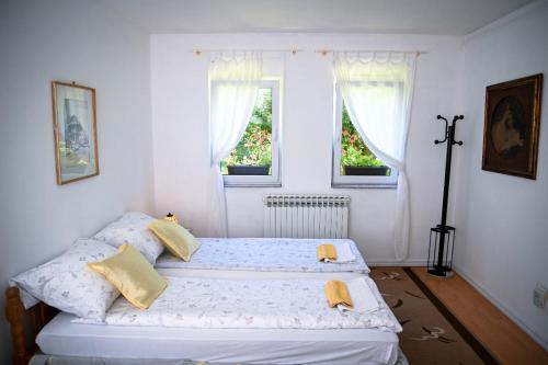 two beds in a white room with two windows at Lalić rooms in Sarajevo