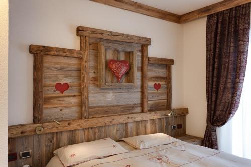 a bedroom with a wooden headboard with hearts on the wall at Alpenhotel Panorama in Campitello di Fassa