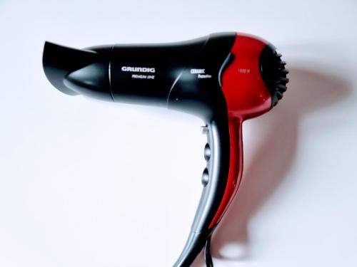 a black and red hair dryer on a white background at have-a-nice-Stay - nahe Bahnhof - 20 Minuten nach Hamburg - trotzdem ruhig gelegen - 6 Minuten zu Fuß ins Zentrum Ahrensburg - modern eingerichtet in Ahrensburg