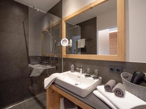 bagno con lavandino, specchio e doccia di Stoaberg Lodge a Sankt Ulrich am Pillersee