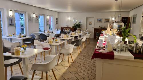 a restaurant with white tables and white chairs at Das kleine Hotel auf Mönchgut in Lobbe