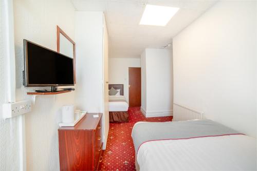 um quarto de hotel com uma cama e uma televisão em OYO The Golden Cheval Hotel & Shisha Bar em Blackpool