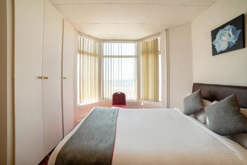 a bedroom with a large bed and a large window at OYO The Golden Cheval Hotel & Shisha Bar in Blackpool