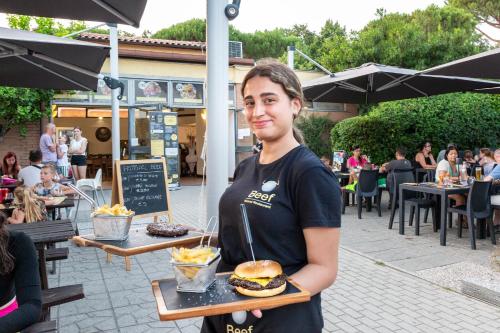 a woman holding a tray of a hamburger and chips at hu I Pini village in Fiano Romano