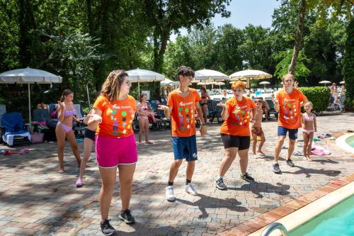 a group of people in orange shirts standing by a swimming pool at hu I Pini village in Fiano Romano