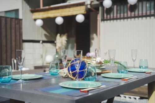a table with plates and wine glasses on it at Kominkayado LOOF Naminoie in Iwada