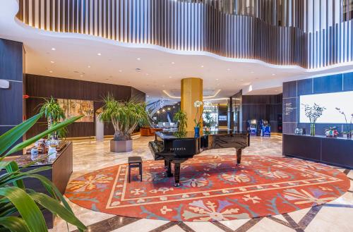 a grand piano in a lobby with plants at Silk Road by Minyoun in Samarkand